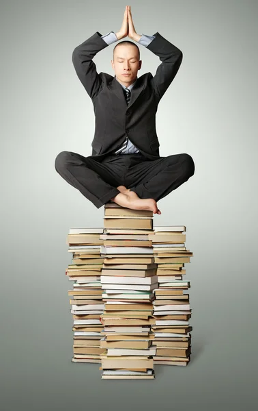 Geschäftsmann in Lotuspose mit vielen Büchern in der Nähe — Stockfoto
