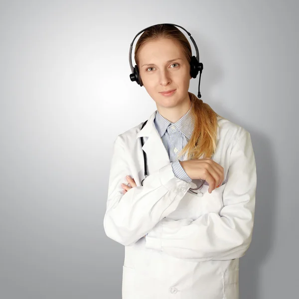 Γυναίκα γιατρό με ακουστικά χαμόγελο στο camera — Φωτογραφία Αρχείου
