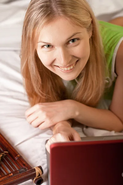 抱着手提电脑躺在床上的妇女 — 图库照片