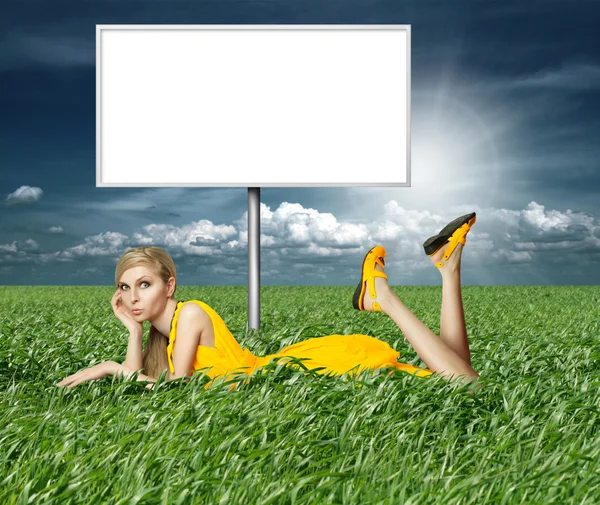 Blondynka w żółtej sukience w zielonej trawie — Zdjęcie stockowe
