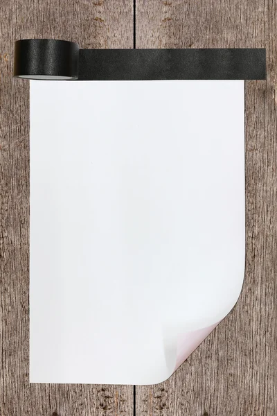 Gebogen papier geplakt door zwarte tape op hout achtergrond — Stockfoto