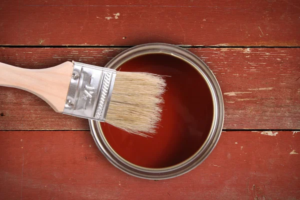 Tinta vermelha pode com escova no fundo da prancha de madeira — Fotografia de Stock