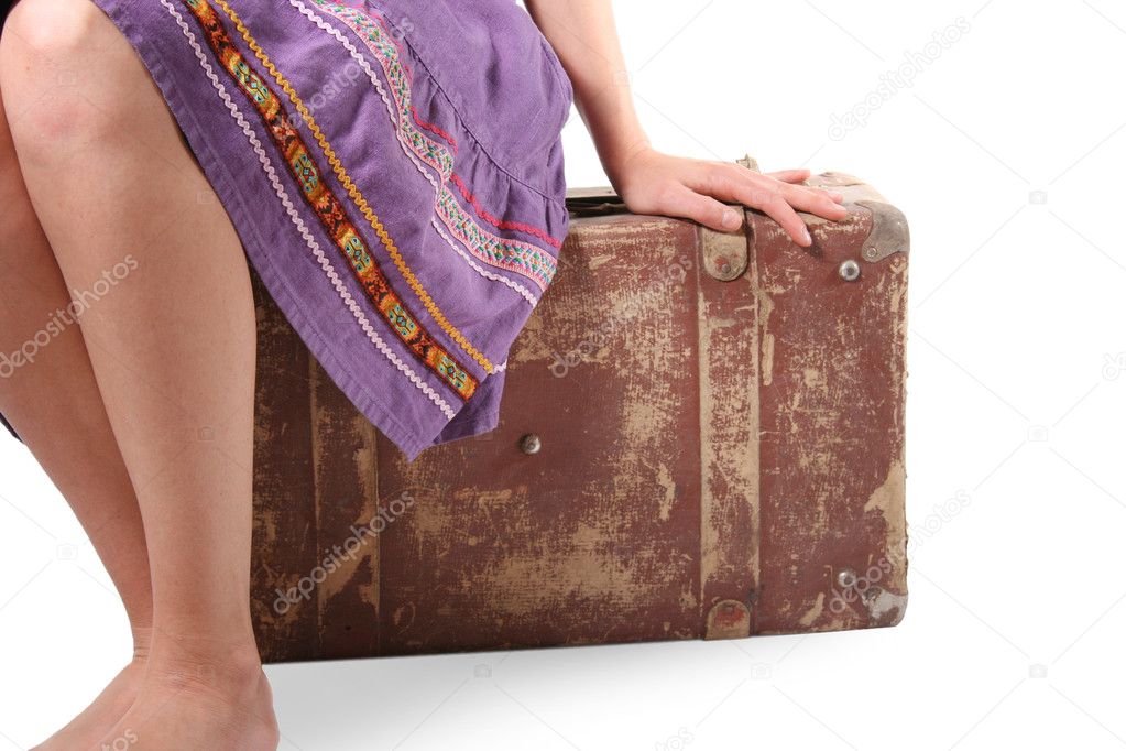 Woman sitting on old suitcase
