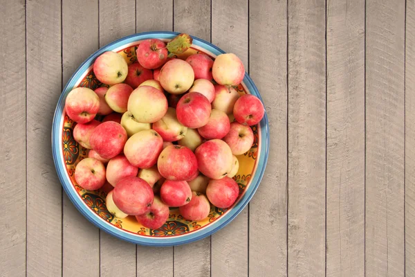 Manzanas en un tazón sobre fondo de madera —  Fotos de Stock