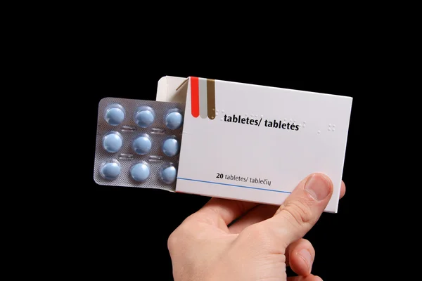 Ręka trzymać opakowanie tabletek na czarnym tle — Zdjęcie stockowe