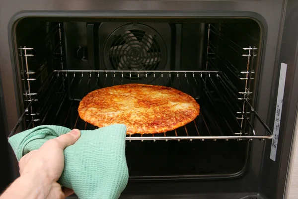 Mão tirar pizza fora do forno — Fotografia de Stock