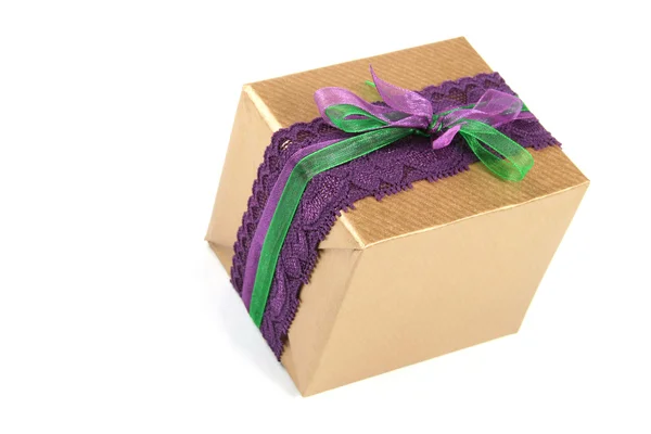 Подарункова коробка, загорнута золотим папером і зав'язана фіолетовим мереживом — стокове фото