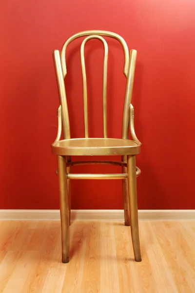 Cadeira de madeira dourada à moda antiga contra a parede vermelha — Fotografia de Stock