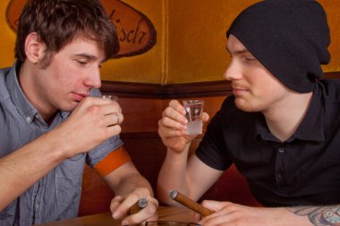 Two friends sitting in a pub drinking a beer and smoking a cigarette clipart