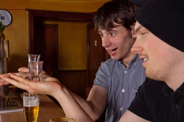 Two friends sitting in a pub and drinking hard liquor clipart