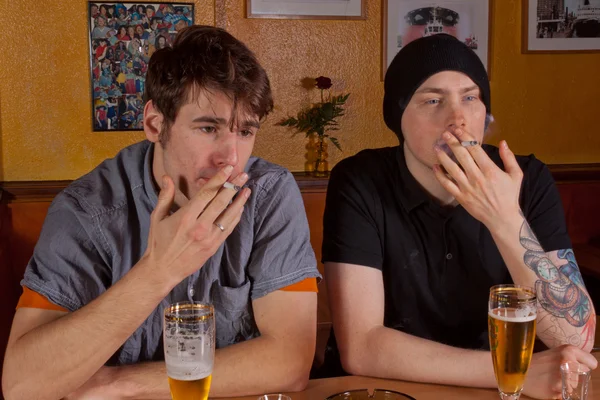 stock image Two friends sitting in a pub drinking a beer and smoking a cigarette