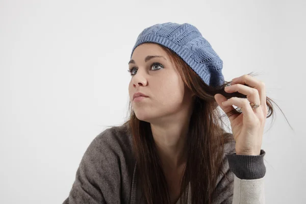 Ung kvinna med blå mössa tittar på kameran — Stockfoto