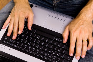 Man sitting on the floor working on laptop computer at home clipart