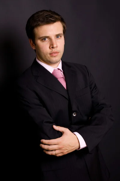 Porträt eines jungen Geschäftsmannes auf schwarzem Hintergrund — Stockfoto