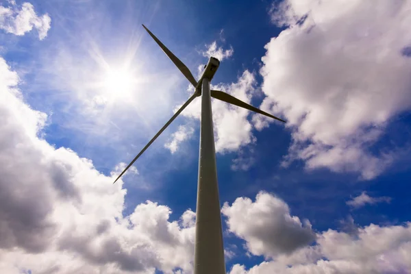 Wind turbine over a cloud filled blue sky, alternative energy so — Stock Photo, Image