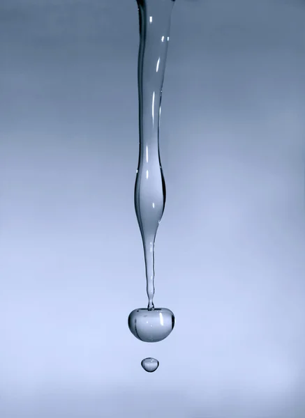 Caída de la gota transparente de agua en un fondo gris — Foto de Stock