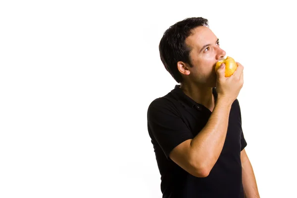 Молодой человек ест свежее красное яблоко, изолированное на белом — стоковое фото
