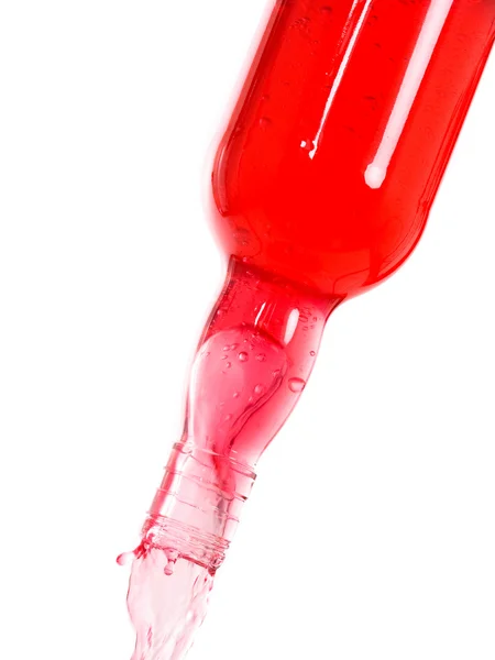 Acqua colorata spruzzata su una bottiglia su bianco — Foto Stock