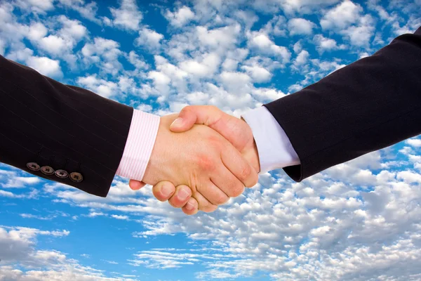 Stock image Business men hand shake over a blue sky with clouds as backgroun