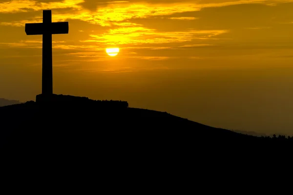 Cross sziluettje egy hegy tetején, a naplemente — Stock Fotó