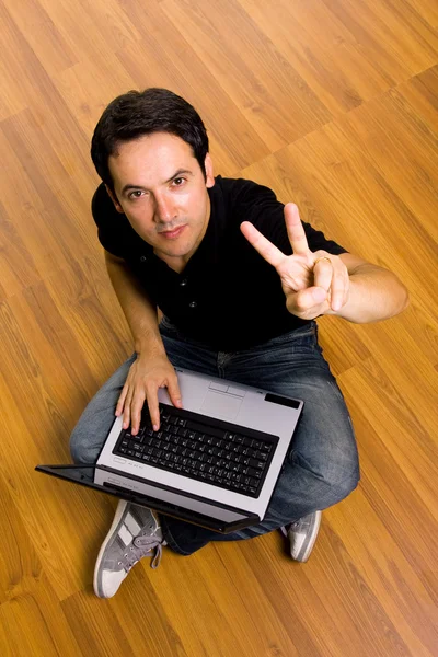 Joven sentado en el suelo trabajando en el ordenador portátil en hom — Foto de Stock