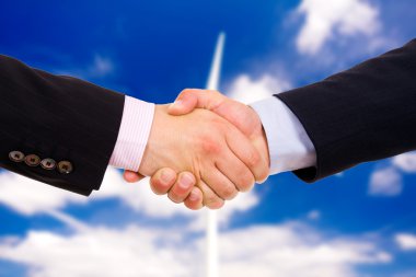 Business men hand shake over a windmill as background clipart