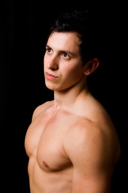 Young sensual man's portrait. Close-up face against black background clipart