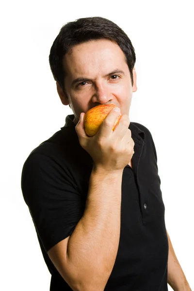 若い男が白で隔離され、新鮮な赤いリンゴを食べる — ストック写真