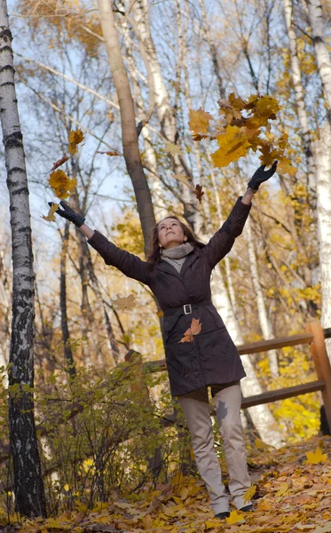 Young woman throwing leaves in the air — Stock Photo, Image