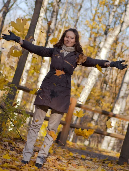 Joven mujer lanzando hojas en el aire —  Fotos de Stock