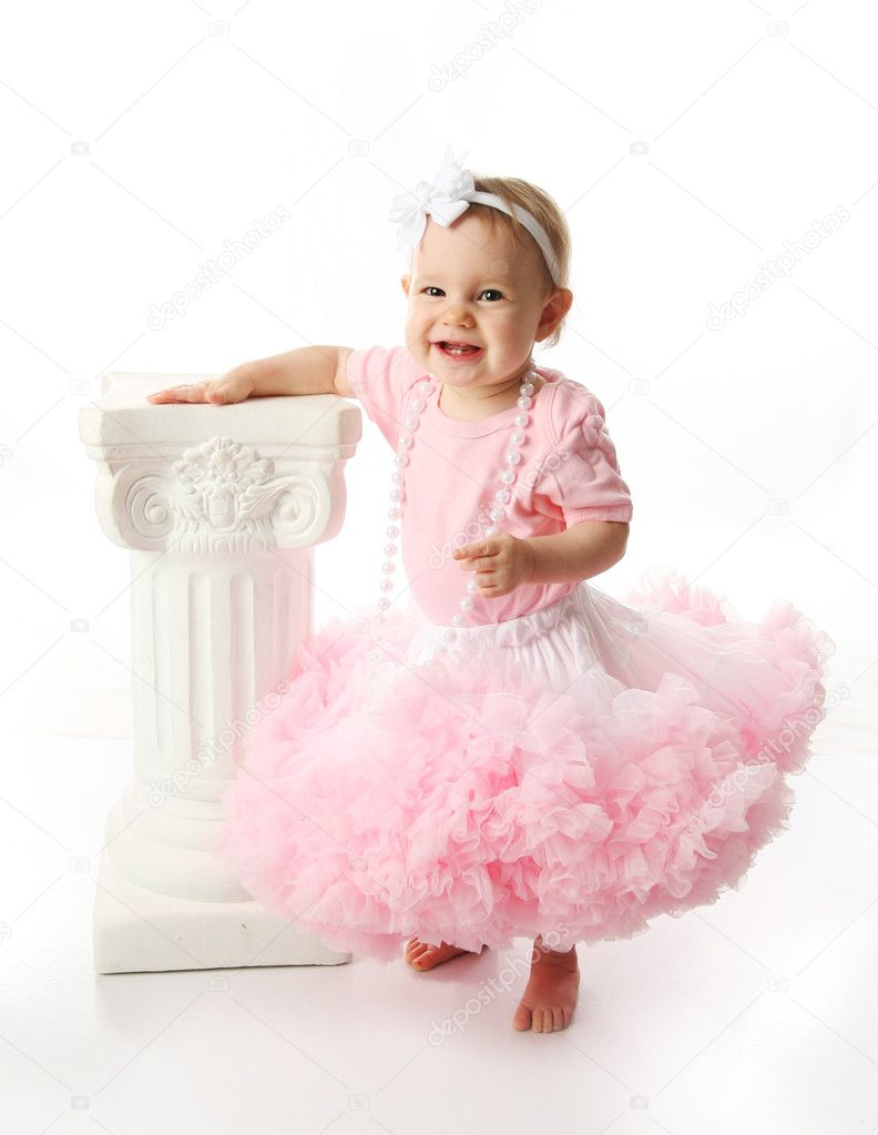Baby girl wearing pettiskirt tutu and pearls standing next to a