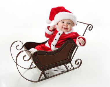 Smilng santa baby sitting in a sleigh clipart