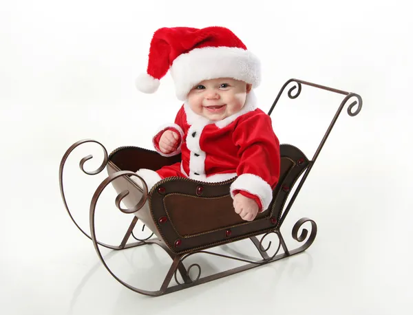 Lachende santa baby zitten in een slee — Stockfoto