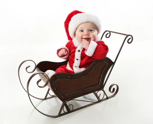 Smiling santa baby sitting in a sleigh — Stock Photo, Image