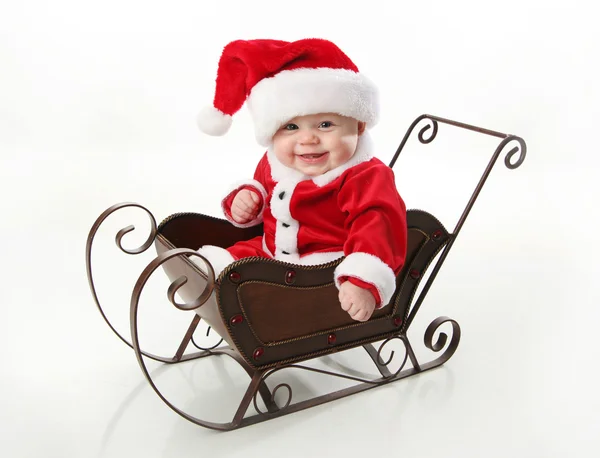 Ler santa baby sitter i en släde Stockfoto