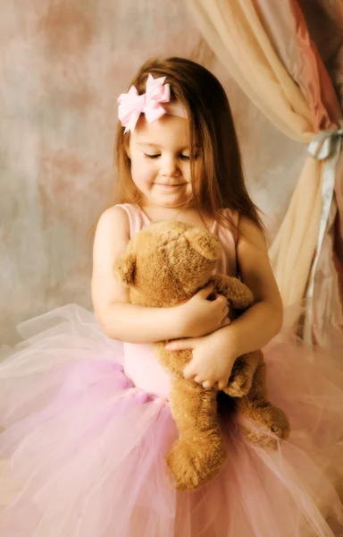 Маленькая балерина обнимает плюшевого мишку — стоковое фото