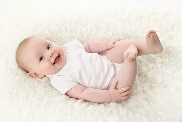 かわいい若い赤ちゃん白い毛布の上に背中に横たわってボディー スーツのシャツを着ての肖像画 — ストック写真