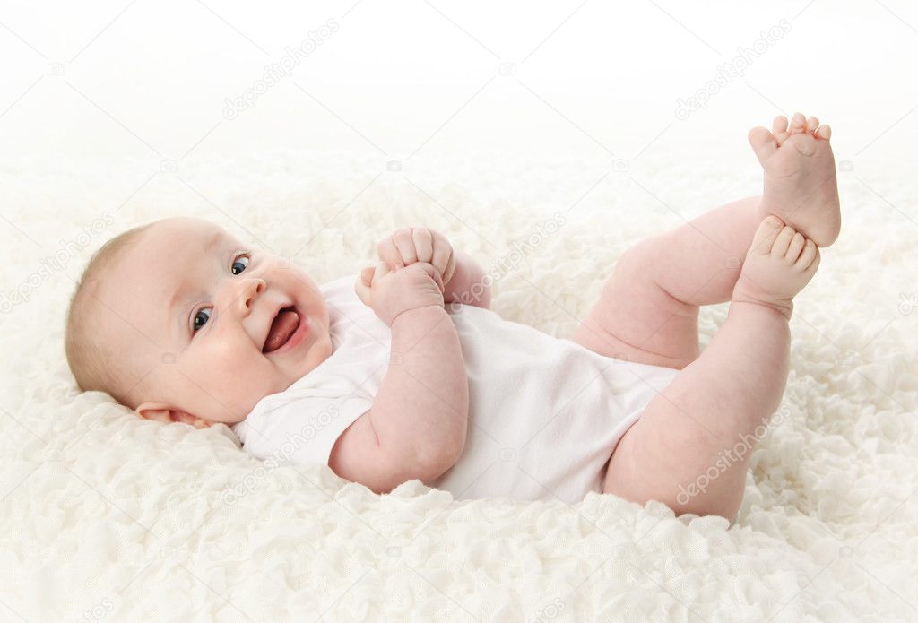 Portrait of a cute young baby lying on back over a white blanket, wearing a bodysuit shirt