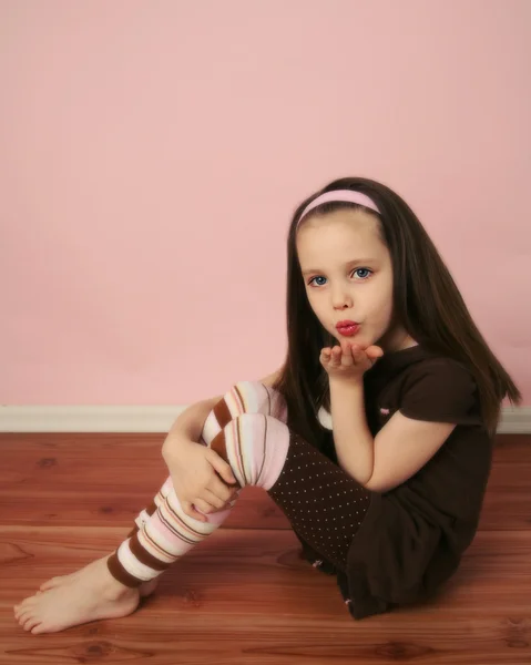 Милая Молодая Девушка Сидящая Деревянном Полу Розовой Стеной Дующая Поцелуй — стоковое фото