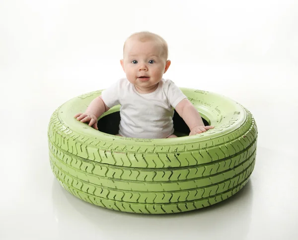 밝은 그린된 타이어 안에 앉아있는 아기 — 스톡 사진