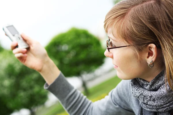 La chica sostiene un teléfono móvil en las manos — Foto de Stock