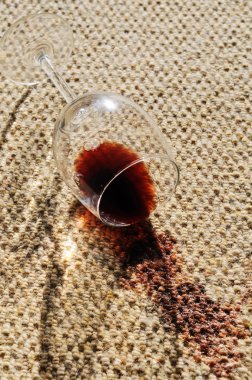 A glass of red wine spilt on a wool carpet. clipart