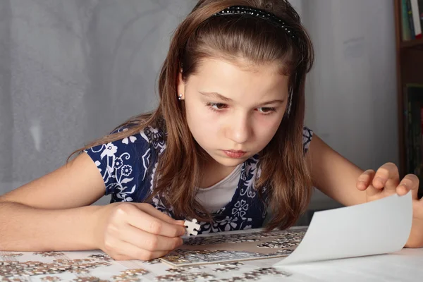 Teenage girl concentrates on puzzle — Stock Photo, Image