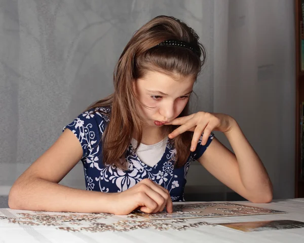 Adolescente chica se concentra en rompecabezas Imagen de archivo