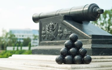 Pyramid of cannonballs on the cannon with Omsk state emblem background clipart