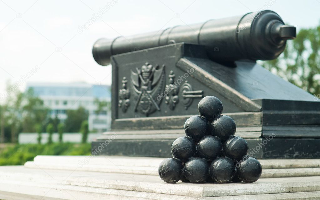 Pyramid of cannonballs on the cannon with Omsk state emblem background
