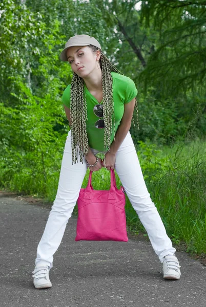 森林の背景にピンクの袋とキャップの美少女 — ストック写真
