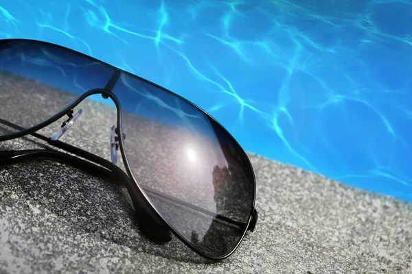 Γυαλιά ηλίου, δίπλα σε μια πισίνα — Φωτογραφία Αρχείου