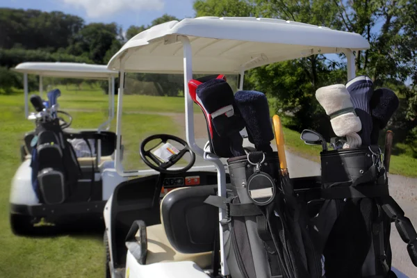 Deux voiturettes de golf avec clubs prêts à partir — Photo