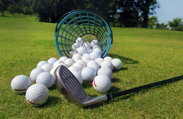 Golf balls pouring out of basket onto grass — Stock Photo, Image